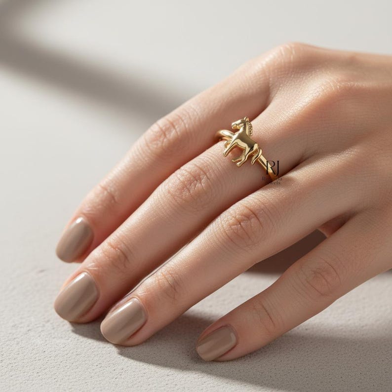 May include: A gold-colored ring featuring a horse design. The ring is worn on a finger, showcasing the detailed equestrian figure. The ring's design is a three-dimensional horse, adding a unique touch to the jewelry.