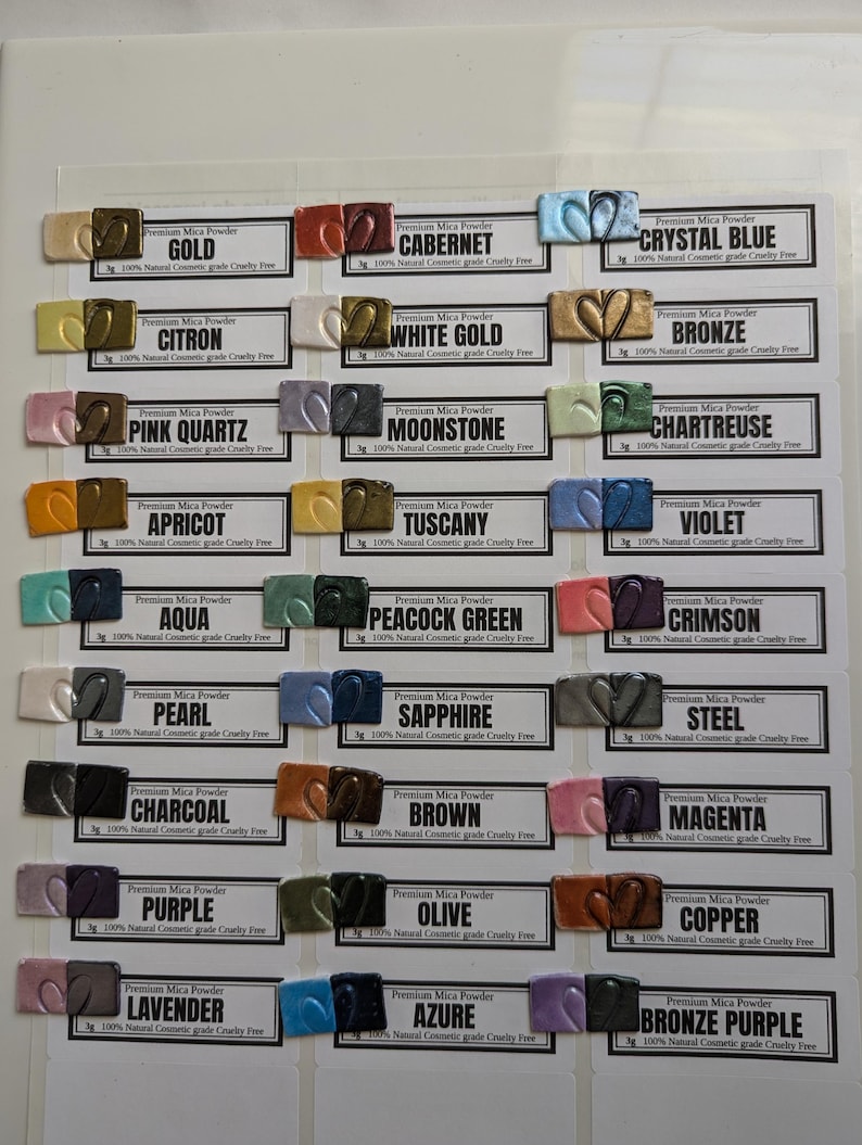 Black and white polymer clay tiles are arranged next to the color of mica powder used to create the metallic, pearlescent or colorful effect.