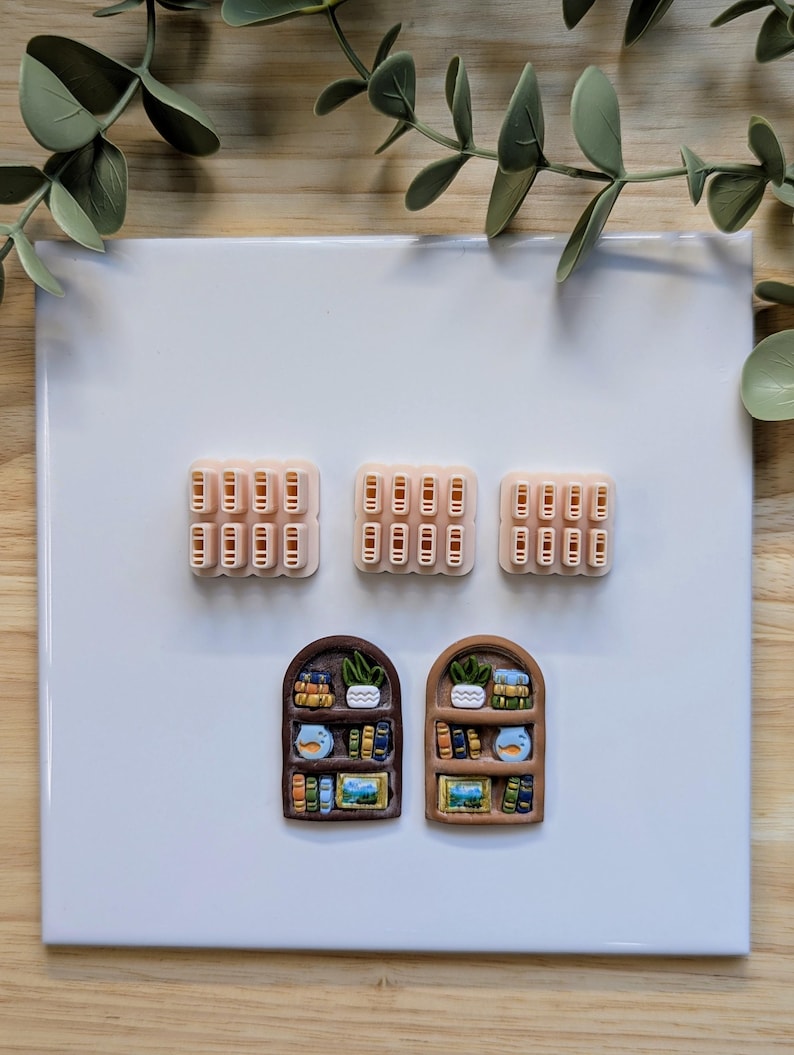 Puede incluir: Una colecci&oacute;n de imanes hechos a mano de arcilla polim&eacute;rica. Los imanes incluyen tres conjuntos de peque&ntilde;as pilas de libros rectangulares en color melocot&oacute;n claro y dos dise&ntilde;os de estanter&iacute;as en miniatura con detalles coloridos.