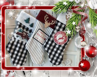 May include: Three Christmas stockings featuring black and white buffalo check patterns and vertical stripes. The stockings are decorated with a red truck graphic, a wooden reindeer cutout, and circular North Pole Air Mail patches with reindeer.