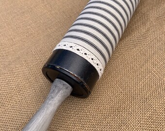 May include: A black and white striped rolling pin with a white lace trim and a gray wooden handle.
