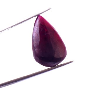 May include: A polished, teardrop-shaped gemstone in deep burgundy, held by silver tweezers. The gem has a smooth, reflective surface with subtle colour variations, transitioning from a lighter shade at the top to a darker hue at the base. Set against a white background.