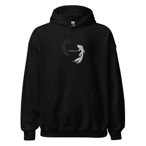 May include: Black hoodie with a white and black fish design on the front. The fish are swimming in a circle, facing each other.