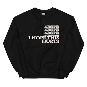 May include: Black sweatshirt with the text "I HOPE THIS HURTS" repeated multiple times in a glitched font.