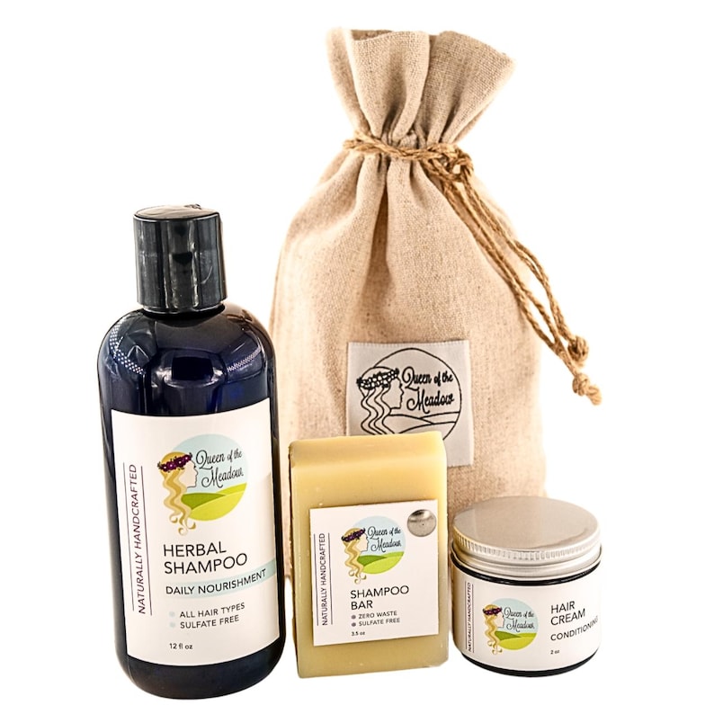 K&ouml;nnte beinhalten: Ein Set nat&uuml;rlicher Haarpflegeprodukte in einem Jutesack. Das Set enth&auml;lt eine 355 ml Flasche Kr&auml;utershampoo, eine Shampoobar und eine Haarbalsamcreme. Die Produkte sind alle mit dem Queen of the Meadow Logo versehen.
