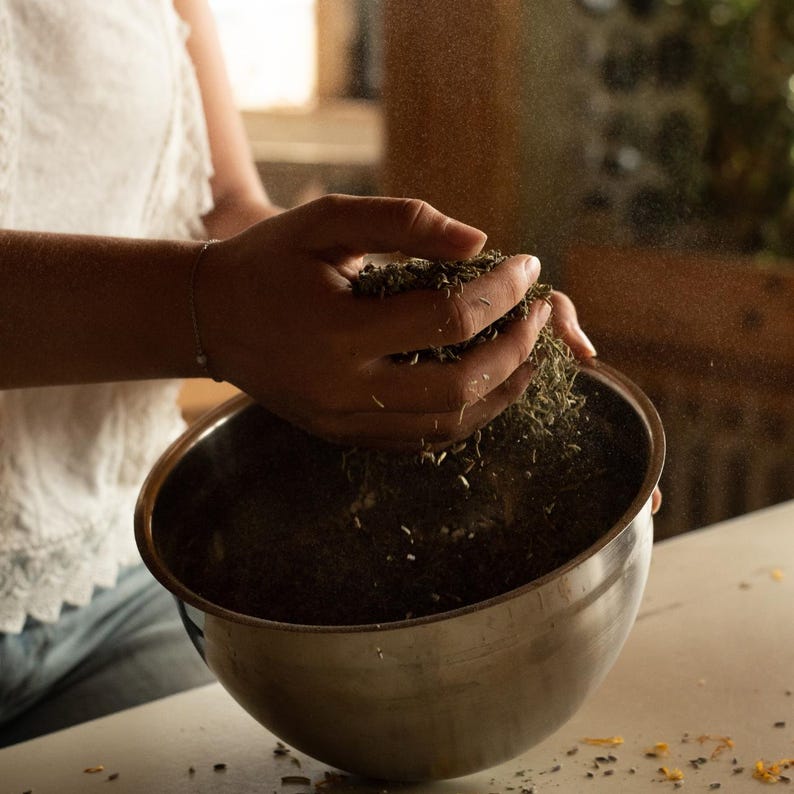 K&ouml;nnte beinhalten: Eine Hand sch&uuml;ttet getrocknete Kr&auml;uter in eine Sch&uuml;ssel aus Edelstahl. Die Kr&auml;uter sind hellbraun und liegen verstreut um die Sch&uuml;ssel herum.