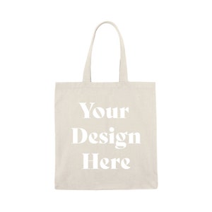 May include: A plain beige canvas tote bag with the text "Your Design Here" printed in white.