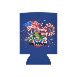 May include: A blue can cooler featuring a green frog wearing a patriotic hat and holding a flag. The design includes fireworks, American flags, and the word "Boricua" in white. The cooler is designed to keep beverages cold.