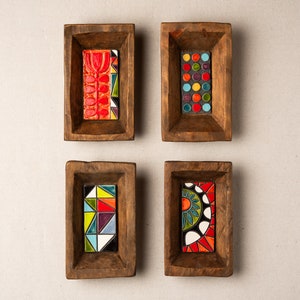 Puede incluir: Cuatro bandejas de madera con incrustaciones de azulejos coloridos. Los azulejos presentan patrones geométricos en rojo, azul, verde, amarillo y blanco. Las bandejas son perfectas para exhibir objetos pequeños o servir aperitivos.