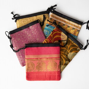 Pode incluir: Cinco bolsas de cord&atilde;o de cor feitas de tecido com padr&otilde;es intrincados. As bolsas s&atilde;o feitas de seda e t&ecirc;m um fecho de cord&atilde;o preto.