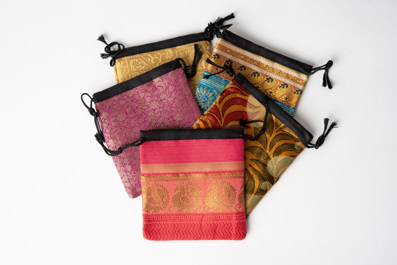 Pode incluir: Cinco bolsas de cord&atilde;o de cor feitas de tecido com padr&otilde;es intrincados. As bolsas s&atilde;o feitas de seda e t&ecirc;m um fecho de cord&atilde;o preto.