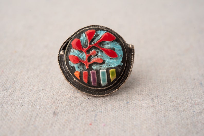 Pode incluir: Um anel de prata com um design de mosaico colorido. O design apresenta um padr&atilde;o floral vermelho e azul com uma fileira de azulejos retangulares coloridos.