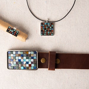 May include: A set of three jewelry pieces featuring a mosaic design with a variety of colorful stones. The set includes a necklace, a ring, and a belt buckle.