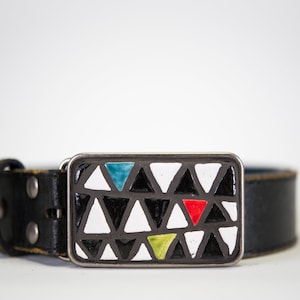 May include: A black leather belt with a silver buckle featuring a geometric design of white, black, red, blue, and green triangles.