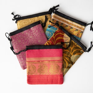 May include: Five colorful drawstring pouches made of fabric with intricate patterns. The pouches are made of silk and have a black drawstring closure.