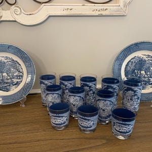 May include: A set of blue and white patterned glasses and two matching plates. The glasses and plates feature a blue and white design of a winter scene with trees and a house.
