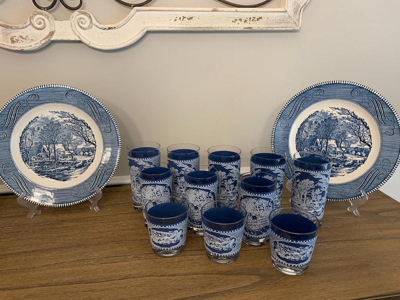 May include: A set of blue and white patterned glasses and two matching plates. The glasses and plates feature a blue and white design of a winter scene with trees and a house.