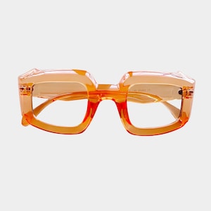 May include: Orange-tinted eyeglasses with a bold, square frame. The glasses have a translucent, plastic frame and a bridge that connects the two lenses. The lenses are clear, and the overall design is modern and stylish.