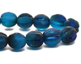May include: A strand of teal blue glass beads with a ribbed texture. The beads have an iridescent finish.