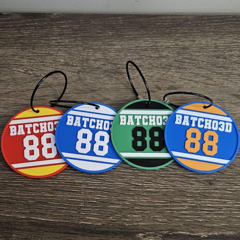May include: Four circular luggage tags with black wire loops. Each tag features the text BATCHO3D and the number 88 in white, black, or orange. The tags are red, blue, green, and blue with yellow, white, black, and orange borders respectively.