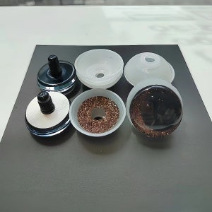 May include: A set of six craft eyes featuring a black pupil and a brown glitter iris. The components include three black plastic backs with threaded stems, two translucent white plastic washers, and one assembled eye with a clear dome cover.