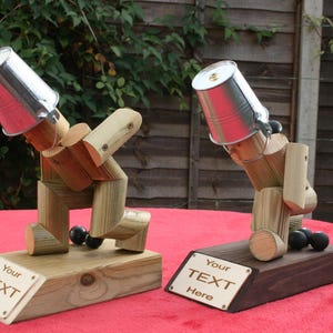 May include: Two wooden bowling trophies with metal buckets on their heads. The trophies are standing on wooden bases with engraved plaques that say "Your Text Here".