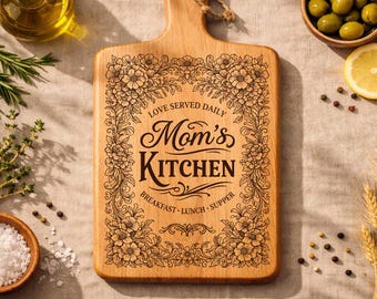 May include: A wooden chopping board with a handle, engraved with "Mom's Kitchen" in a decorative font, framed by floral patterns. The board is surrounded by ingredients like olives, lemons, and herbs.