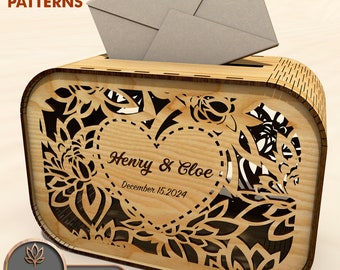 May include: A wooden box with a heart-shaped cutout and floral design. The box has a slot for envelopes and is personalised with the names "Henry & Chloe" and the date "December 15, 2024".