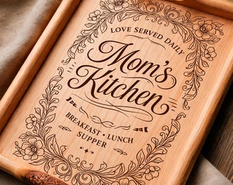 May include: Light brown wooden serving tray with handles, engraved with "Mom's Kitchen" and floral details. The tray features the words "Love Served Daily" and "Breakfast, Lunch, Supper".