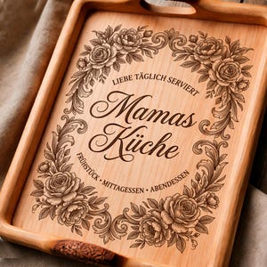 May include: Wooden serving tray with engraved floral design and the words "Liebe täglich serviert Mamas Küche Frühstück Mittagessen Abendessen". The tray has handles and a light brown finish.