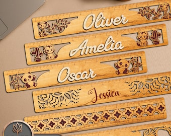 May include: Wooden rulers with personalized names and decorative animal cutouts. Each ruler features a different name, such as "Oliver," "Amelia," and "Oscar," along with animal designs like a giraffe, cat, and panda. The rulers are marked with inch measurements.