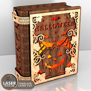 May include: A wooden Halloween-themed book-shaped box with intricate laser-cut designs. The front features a jack-o'-lantern and the word "HALLOWEEN". Bats and leaves are also cut into the wood. The box is brown with a lighter wood border.