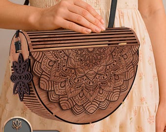 May include: A wooden crossbody bag with a detailed mandala design. The bag is made of light brown wood with a dark brown strap and a decorative flower-shaped accent. The bag has a curved shape and a laser-cut design. The text "LASER BUILD.LAB TEMPLATE LASER CUT" is visible.