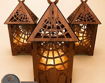 May include: Three wooden Halloween lanterns with laser-cut detailing. Each lantern has a triangular roof with a spiderweb design, a circular handle, and a warm, glowing light inside. The text "SET OF 3" is visible.