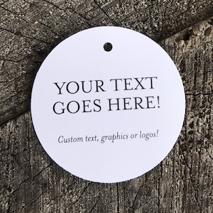 Puede incluir: Etiqueta redonda blanca con un agujero en la parte superior. La etiqueta dice "YOUR TEXT GOES HERE!" y "Custom text, graphics or logos!"
