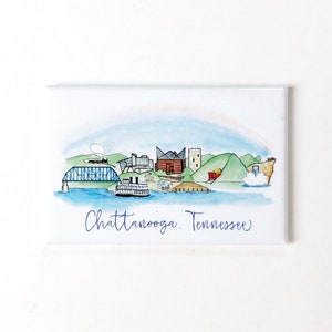 May include: A watercolor illustration of the Chattanooga, Tennessee skyline. The illustration features a bridge, buildings, a boat, and hills. The text "Chattanooga, Tennessee" is written in blue cursive.
