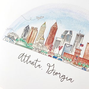 Pode incluir: Uma ilustra&ccedil;&atilde;o de aquarela do horizonte de Atlanta, Ge&oacute;rgia. A ilustra&ccedil;&atilde;o apresenta v&aacute;rios edif&iacute;cios, incluindo o edif&iacute;cio do Capit&oacute;lio do Estado, o World of Coca-Cola e o Aqu&aacute;rio da Ge&oacute;rgia. A ilustra&ccedil;&atilde;o tamb&eacute;m inclui um avi&atilde;o voando por cima, carros dirigindo na rua e &aacute;rvores.