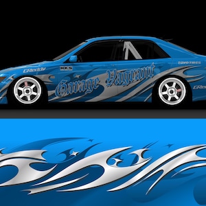 Puede incluir: Un coche azul con una envoltura personalizada que presenta un diseño de llamas plateadas y azules. El coche tiene las palabras "Garage Vagrant" y "HKS" en el lateral. El coche está sobre un fondo azul.