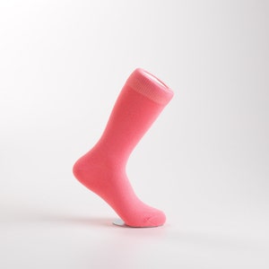 May include: A single pink sock with a white top band. The sock is displayed on a white background.