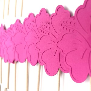 May include: Pink paper hibiscus flower cupcake toppers on wooden sticks.