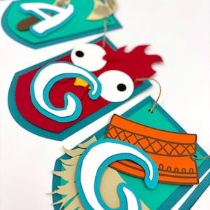 May include: A colourful paper banner with the word "Moana" spelled out in large, white letters. Each letter is decorated with a different design, including a rooster, a flower, and a coconut.