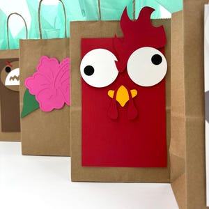 May include: Brown paper gift bags with decorative cutouts. One bag features a red rooster design with white eyes and a yellow beak. Other bags have a pink flower and a bear face. Each bag has a brown handle and is filled with teal tissue paper.
