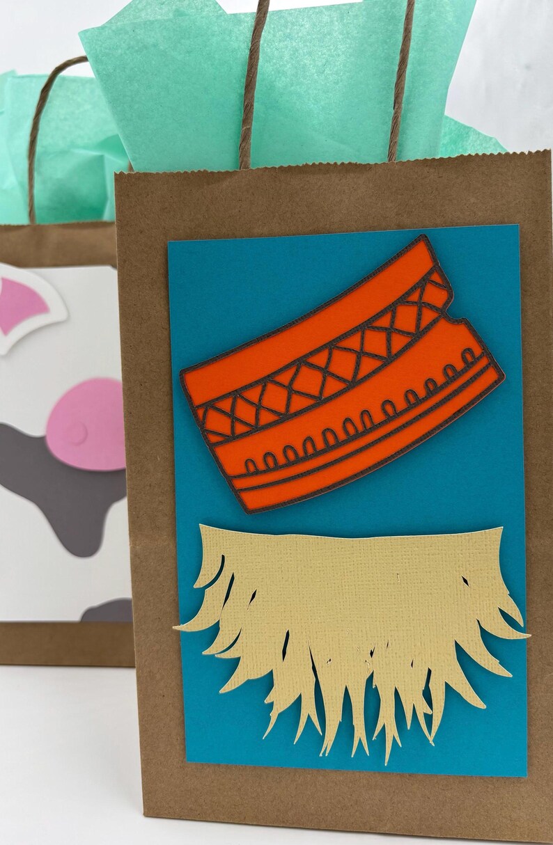 May include: Brown paper gift bags with teal tissue paper and brown twine handles. One bag has a blue rectangle with an orange design and a tan cutout. Another bag has a cow face design.