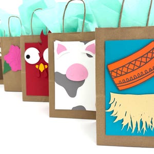 May include: A row of brown paper gift bags with various animal and themed cutouts. Each bag has a different design, including a bird, bear, flower, rooster, cow, and a design with an orange pattern and yellow fringe. The bags are filled with light blue tissue paper.