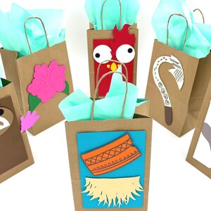 May include: A collection of brown paper gift bags with various colorful designs. Each bag features a different cutout, including a pink flower, a red character, and a white and brown hook. The bags are filled with light blue tissue paper.