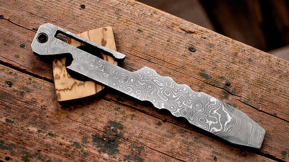A Damascus-steel prybar that opens bottles, pries things, and looks like a artifact from a fantasy blacksmith — EDC utility meets forge art.
