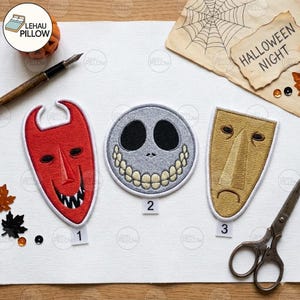 May include: Three embroidered patches featuring character masks: a red devil mask labeled 1, a round grey skull face with a wide grin labeled 2, and a gold-toned elongated mask with a sad expression labeled 3, arranged on a white surface.