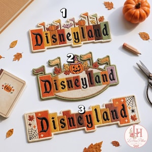 May include: Three embroidered patches featuring the word Disneyland in black gothic lettering. Patch 1 has pumpkins and flags. Patch 2 features a central pumpkin with a witch hat. Patch 3 includes spiderwebs, stars, and autumn leaves in orange and brown.