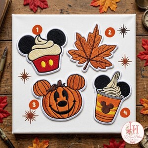 May include: Four embroidered patches on a white canvas. Patch 1 is a cupcake with black mouse ears. Patch 2 is an orange maple leaf. Patch 3 is a pumpkin with mouse ears and a face. Patch 4 is a cup with mouse ears and a swirl of soft serve.