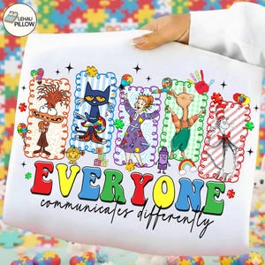 以下が含まれることがあります： カラフルな漫画のキャラクターと「EVERYONE communicates differently」の文字がプリントされた白い枕カバー。ピート・ザ・キャット、キャット・イン・ザ・ハットなどのキャラクターと、パズルピースや虹のアクセントがデザインされています。